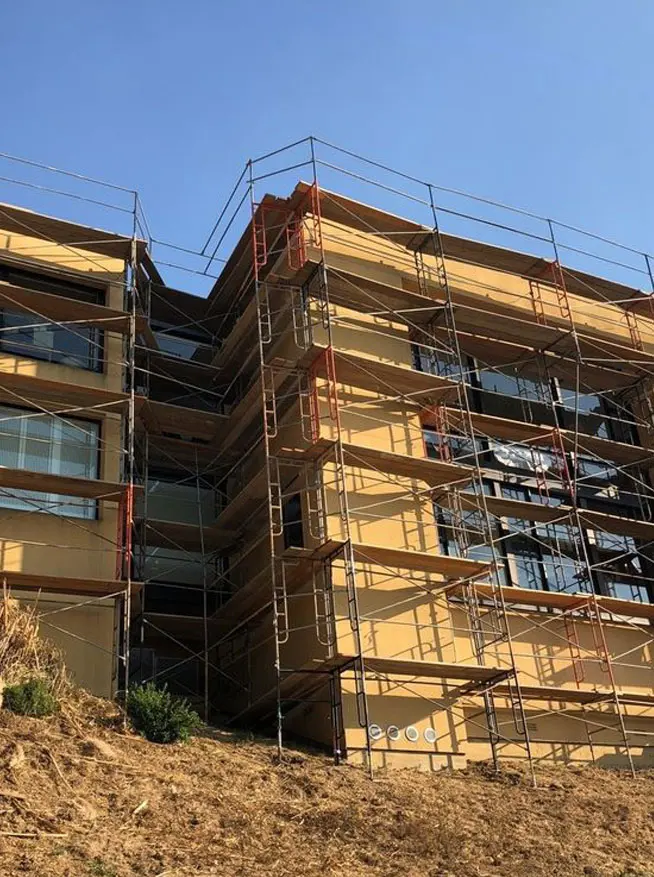 Hillside apartment building exterior supported by multi-level scaffolding installed by Los Angeles Elite Scaffolding for exterior renovation work.