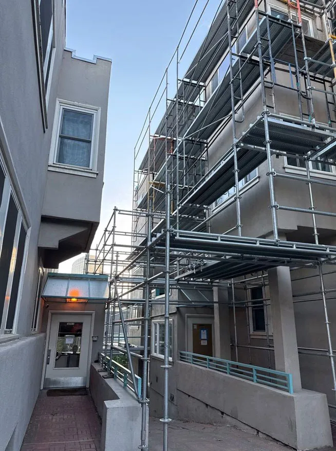 Scaffolding system set up in a tight walkway between buildings by Los Angeles Elite Scaffolding to provide safe access for exterior repairs.